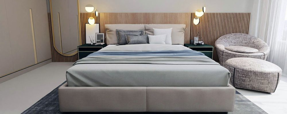 Sophisticated residential bedroom interior in Dubai, featuring a modern bed with plush bedding, wooden accent wall, stylish nightstands with lamps, and a cozy chair by large windows with sheer curtains.